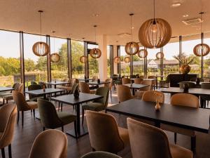 ein Restaurant mit Tischen und Stühlen und großen Fenstern in der Unterkunft in2 The Hotel in Xanten