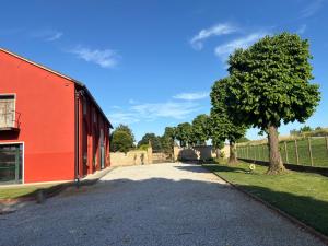 a red building and a tree next to a fence at Ca' San Valentino in Pontelongo