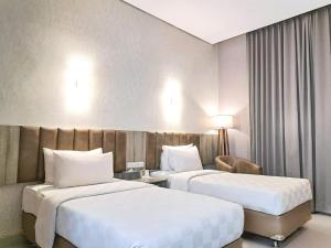 a hotel room with two beds and a chair at Raden Wijaya Hotel & Convention in Mojokerto +33 photos
