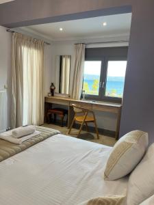 a bedroom with a bed and a desk and a window at AMORÉA Jacuzzi Suites Evia in Eretria