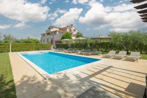 a swimming pool with chairs and a house in the background at Apartment Complex Vetrina-Shared Pool in Nova Vas
