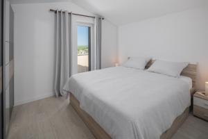 a white bedroom with a large bed and a window at Apartment Complex Vetrina-Shared Pool in Nova Vas +10 photos