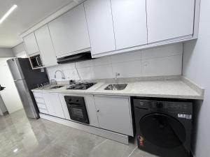 a kitchen with white cabinets and a dishwasher at Apartamento 2 quartos na baixada in São Vicente
