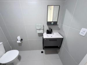 a white bathroom with a toilet and a sink at Apartamento 2 quartos na baixada in São Vicente +3 photos