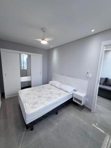 a white bedroom with a bed and a mirror at Apartamento 2 quartos na baixada in São Vicente