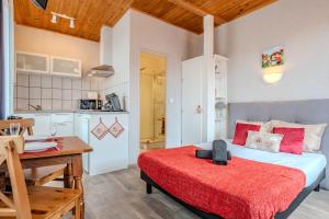 a bedroom with a bed and a desk and a kitchen at PINOT GRIS - Charmant studio au cœur du vignoble - parking gratuit in Riquewihr