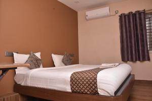 a bedroom with a bed with white sheets and a window at Le Grace Bye Pass in Madurai