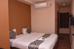 a hotel room with a bed with a white bedspread at Le Grace Bye Pass in Madurai +4 photos