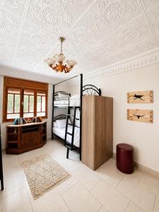 a bedroom with bunk beds and a ceiling with a chandelier at Santacruz Surf Camp Morocco in Tamraght Ouzdar