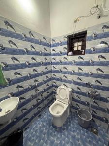 a bathroom with a toilet and a sink with dolphins on the wall at Mcday serviced villa in Varkala