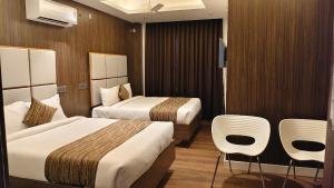 a hotel room with two beds and two chairs at Le Grace Bye Pass in Madurai