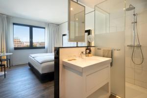 a white bathroom with a sink and a shower at INNSiDE by Meliá Hamburg Hafen in Hamburg