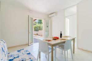 a white dining room with a white table and chairs at La villetta 451 in Fontanelle