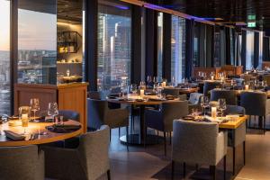 a restaurant with tables and chairs and a view of the city at Meliá Frankfurt City in Frankfurt
