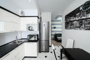 a kitchen with white cabinets and a stainless steel refrigerator at Urban Nest in Chişinău