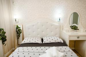 a bedroom with a bed with a white headboard and a mirror at Urban Nest in Chişinău