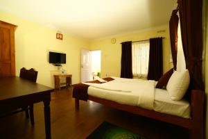 a bedroom with a bed and a desk and a television at Holiday Heaven Munnar in Chinnakanal
