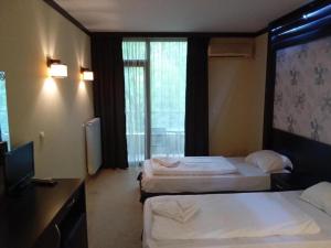 a hotel room with two beds and a flat screen tv at Park Hotel Stratesh in Lovech +35 photos