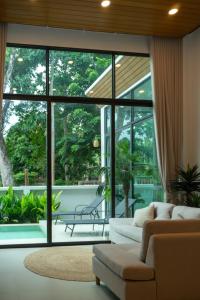 a living room with a couch and a large window at Neon Villa in Ko Phangan