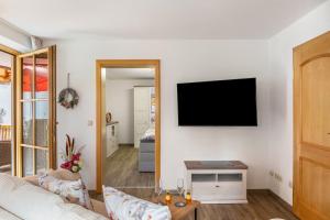 a living room with a couch and a tv on a wall at Haus Christian und Hanni in Bad Kohlgrub