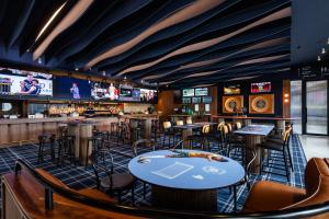 a bar with tables and chairs and televisions at Hotel Panorama in Clapham