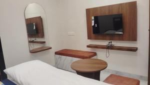 a room with a bed and a tv and a table at Hotel G17 Dhamnod in Dhāmnod