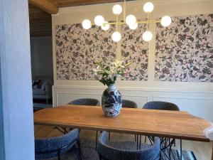a vase of flowers on a wooden table with chairs at Villa Bourbon Pointu - Hiking & Spa in La Plaine des Palmistes