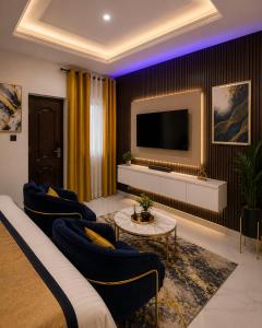 a living room with blue chairs and a tv at Palazzo Apartments in Ikeja
