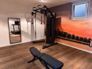 ein Raum mit einem Fitnessraum mit Bank und Spiegeln in der Unterkunft in2 The Hotel in Xanten