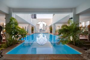 a swimming pool in a house with palm trees at Phnom Penh Katari Hotel in Phnom Penh