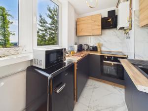 a kitchen with black and white appliances and a window at Śląskie Mieszkania in Będzin +6 photos