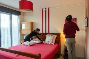 two people in a bedroom putting pillows on a bed at La Pierraille in Froid-Chapelle