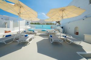 a patio with chairs and umbrellas on a house at Pantelia Suites in Fira