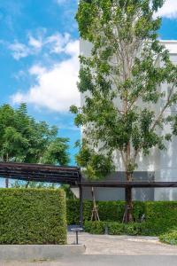 a tree in front of a white building at Gate43 Airport Hotel in Lat Krabang