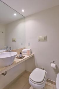 a bathroom with a sink and a toilet and a mirror at Almarena Madero Urbano, Affiliated by Meliá in Buenos Aires