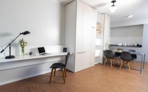 a white kitchen with a desk with a laptop and chairs at Almarena Madero Urbano, Affiliated by Meliá in Buenos Aires