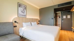 ein Schlafzimmer mit einem großen weißen Bett und einem Stuhl in der Unterkunft TULIP Hotels & Residences - Marne-la-Vallee Torcy in Torcy