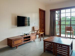a living room with a table and a tv on a wall at Serene Slopes in Vagamon