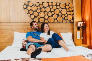 a man and a woman sitting on a bed at Hotel Srdiečko in Tale