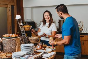 a man and woman standing in a kitchen preparing food at Hotel Srdiečko in Tale +74 photos