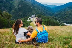 a man and woman sitting on a hill with a backpack at Hotel Srdiečko in Tale