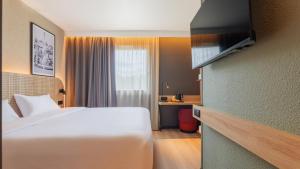 ein Hotelzimmer mit einem weißen Bett und einem Fenster in der Unterkunft TULIP Hotels & Residences - Marne-la-Vallee Torcy in Torcy