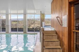 a bathroom with a swimming pool with a staircase and windows at Keepers Cottage - Dartmouth Golf and Spa Resort in Dartmouth