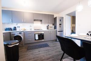 a kitchen with gray cabinets and a table and chairs at Spacious Luxurious Serviced Accommodation 2 in Coventry