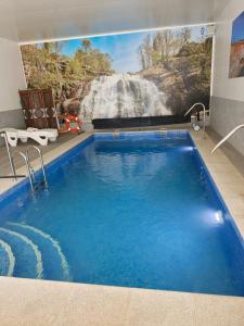 a large swimming pool with a waterfall mural on the wall at Apartamentos La Bodega in La Zarza