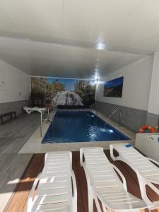 a large swimming pool with two white chairs and a swimming pool at Apartamentos La Bodega in La Zarza