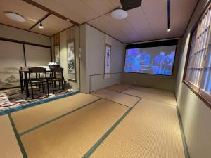 a living room with a tv and a dining room at Hot Spring Inn Hyoutan in Kusatsu