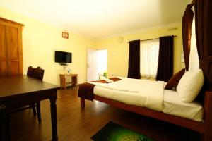 a bedroom with a bed and a desk and a television at Holiday Heaven Munnar in Chinnakanal +19 photos