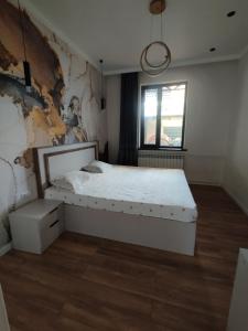 a bedroom with a white bed and a window at Aziz House in Naryn