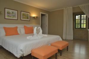 a bedroom with a large white bed with orange accents at Hotel Gastronómico Casa Rosalia in Brion +108 photos